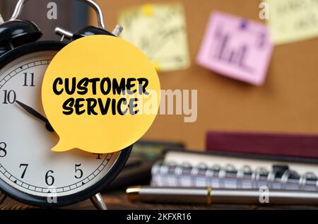 Business concept. The alarm clocks have a sticker with the inscription - Customer Service. There are office items in the background in a blurry backgr Stock Photo