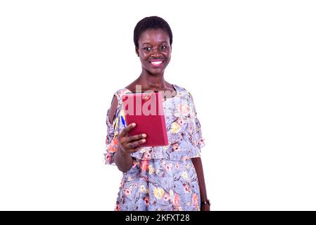 portrait of a beautiful young female student holding a book while smiling. Stock Photo