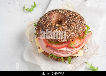 bagel filled with rocket, turkey ham, cream cheese and tomato Stock Photo