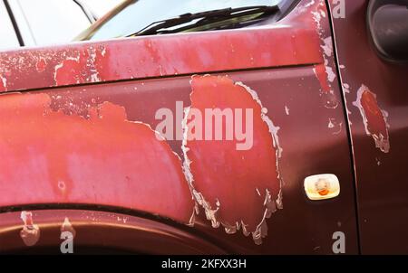 Deteriorated car paint fade and lacquer peeling off of the red truck Stock Photo