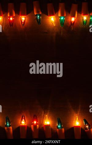 Christmas Lights - Strings of vintage multicolored light bulbs on dark wooden background with space for text Stock Photo