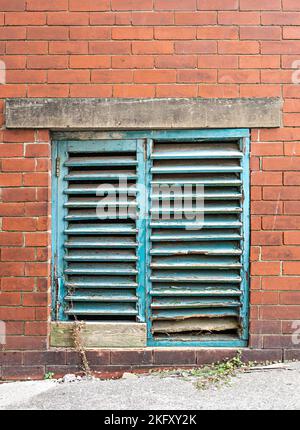 Old Louvre shutters to window of commercial building Stock Photo