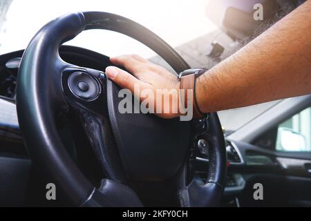 Driver hand pressing on steering wheel honking horn Stock Photo