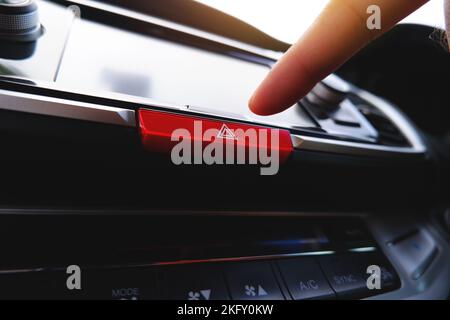 Pressing the emergency light button with the driver hand in the car Stock Photo