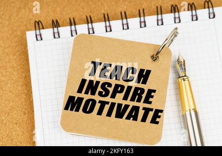 Business and economy concept. There are two notebooks and a pen on the table. On the top notepad, the inscription - Teach Inspire Motivate Stock Photo