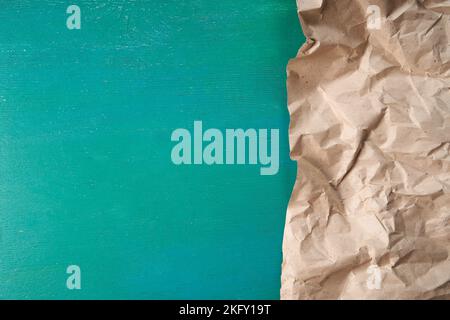 Half of crumpled eco-friendly packaging paper on a green wooden background. An excellent blank for your text or your design. Copy Space. The concept of ecology, recycling, zero waste. Stock Photo