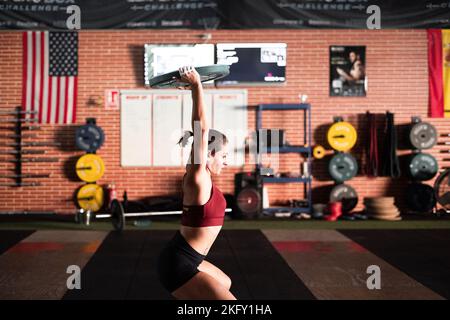 caucasian girl doing sports crouching with her arms outstretched with a big round epsa on her head Stock Photo