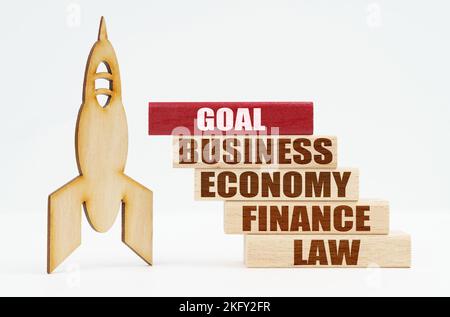 Business and finance concept. On the white surface there is a wooden rocket and planks, on the red plaque the inscription - Goal Stock Photo