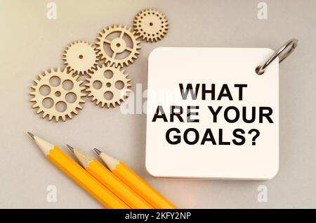 Business and finance concept. On the table are gears, pencils and a notebook with the inscription - What Are Your Goals Stock Photo