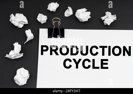 Industrial concept. On a black background, there are crumpled pieces of paper and paper with the inscription - Production Cycle Stock Photo