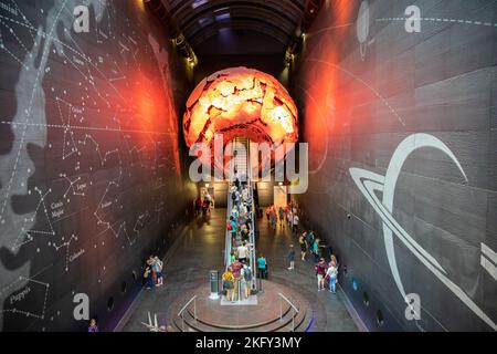 The visitors taking an escalator to the Earth Hall through a red globe in the Natural History Museum, London Stock Photo