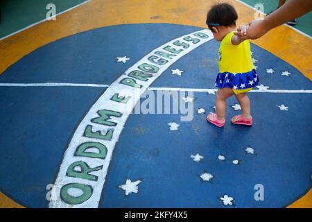 Manaus, Brazil. 19th Nov, 2022. Soccer, World Cup 2022 in Qatar. A little girl in a soccer dress walks over the symbol of the Brazilian national flag with the words 'Ordem e Progesso' (Order and Progress). Credit: Lucas Silva/dpa/Alamy Live News Stock Photo