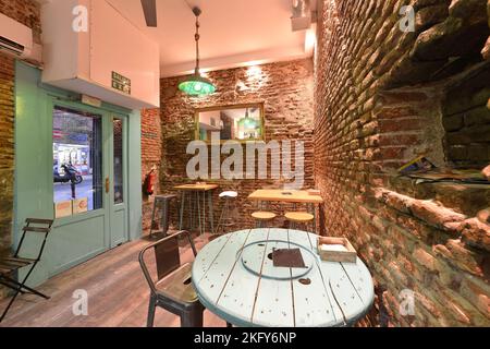 Wooden restaurant table painted in sky blue chalk color lots of matching stools and exposed brick walls Stock Photo