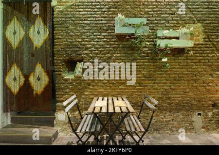 Dining table with wooden and metal folding benches in a bohemian style restaurant with exposed brick walls Stock Photo