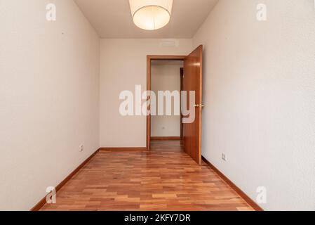 Empty living room with reddish parquet flooring with matching skirting and wooden doors Stock Photo