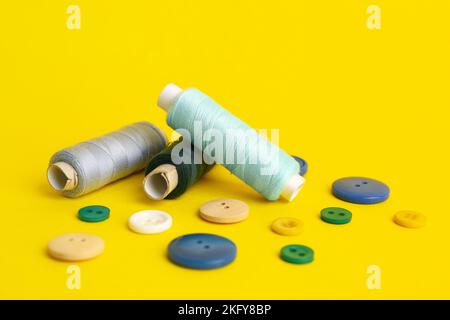 Thread spools and different buttons on yellow background Stock Photo