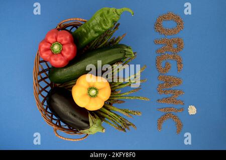 formation of the word organic with legumes and cereals next to a wicker basket with vegetables Stock Photo