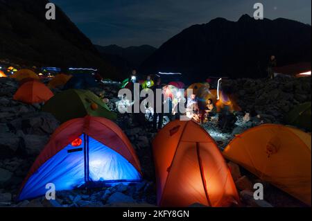 Tents lit up from inside, and the mountains behind them, at night at the capground at Karasawa Cirque on a busy autumn weekend in the Japan Alps. Stock Photo