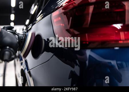 Employee of a car detailing studio polishes the paint of a car  Stock Photo