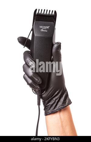 Hairdressers hand in black rubber glove holds hair clipper. Isolated on white background, close up Stock Photo