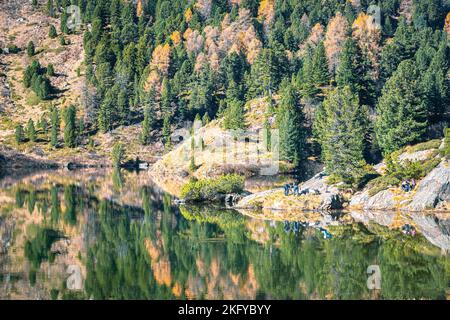 People recreate on the shore of the idyllic Lake Cavloc, near the Maloja Pass in canton Graubünden, Switzerland. Stock Photo