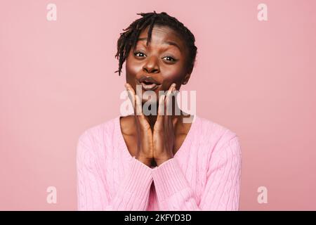 Black excited woman with dreadlocks expressing surprise at camera isolated over pink background Stock Photo