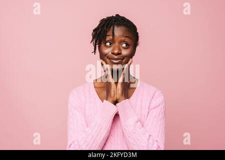 Black young woman with dreadlocks smiling and looking aside isolated over pink background Stock Photo