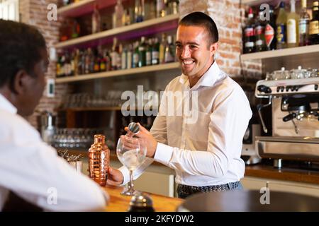 Barkeeper serving visitor in the bar Stock Photo
