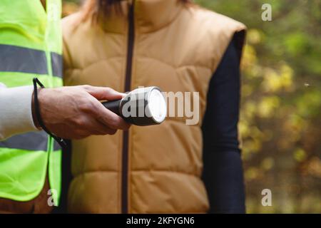 Search and rescue squad of volunteers with a flashlight in forest, close-up on flashlight in hand Stock Photo