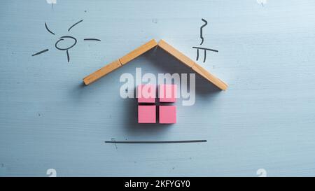 A house made of pink wooden blocks with a hand drawn chimney and sun above it over blue background. Conceptual of real estate and insurance. Stock Photo