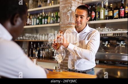 Barkeeper serving visitor in the bar Stock Photo