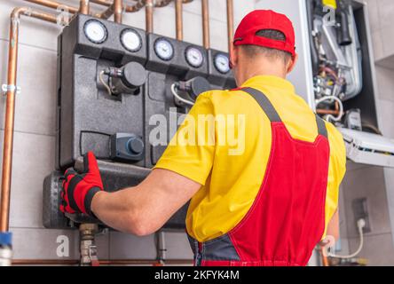 Professional Maintenance Technician Checking Water Heating Installation in Mechanical Room of Commercial Building. Stock Photo
