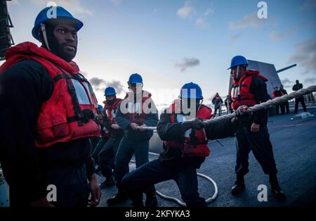 NORTH SEA (Oct. 15, 2022) Sailors heave line during a simulated man overboard drill on the forecastle of the Arleigh Burke-class guided-missile destroyer USS Roosevelt (DDG 80), Oct. 15, 2022. Roosevelt is on a scheduled deployment in the U.S. Naval Forces Europe area of operations, employed by U.S. Sixth Fleet to defend U.S., allied and partner interests. Stock Photo