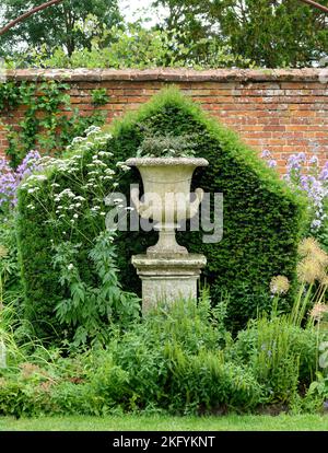 Summer Portrait view of walled garden with ornate urn and hedge in Helmingham Hall and Gardens Suffolk Stock Photo