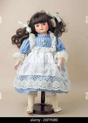 Garham, Germany. 18th Nov, 2022. In this photo illustration, a vintage porcelain doll girl with brown eyes brunette with braided ribbons in a blue dress with white vertical stripes and a lace apron. Porcelain dolls appeared in the 18th century in France. They were used to promote French fashion in the world. Usually such dolls were supplied with a large number of clothes and sent to customers as mini mannequins. (Photo by Igor Golovniov/SOPA Images/Sipa USA) Credit: Sipa USA/Alamy Live News Stock Photo