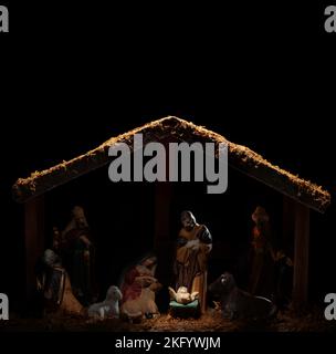 Dimly lit stable showing the Christian nativity scene with the baby Jesus glowing in light. Blank space above for text. Stock Photo