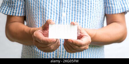 Man holding a white business card with both hands. Stock Photo