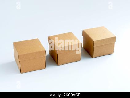 Three cardboard boxes isolated on white background. Carton gift box. Square kraft paper box with lid on top. Delivery, parcel, packaging with online s Stock Photo