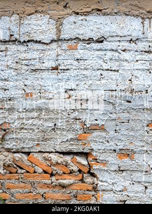 Abstract white grunge peeling cement texture on brick wall background vertical style. Old crack plaster concrete wall. Broken stonewall wallpaper. Stock Photo