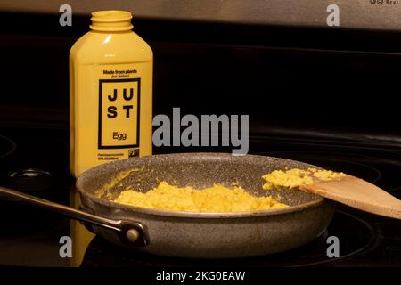 Scrambled "eggs" made with JUST Egg plant-based scramble in a pan on an electric stove. Eat Just Inc. develops vegan alternatives to conventionally... Stock Photo
