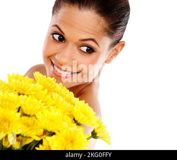 She loves surprises. A beautiful young woman holding a bouquet of yellow flowers and smiling against a white background. Stock Photo