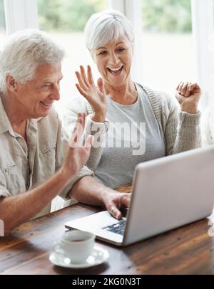 Its so great to see the grandkids. A cheerful senior couple having a video chat on a laptop. Stock Photo