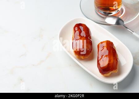 Two caramel eclairs on a white plate Stock Photo
