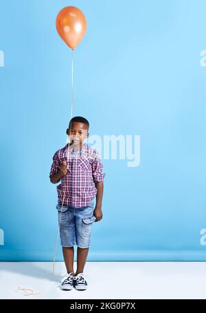 Every little boy is a superhero. a young boy holding a balloon over a blue background.