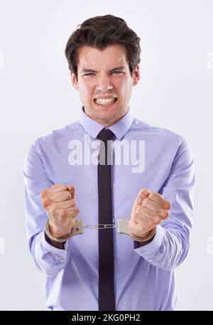 Modern slavery comes in may forms. Studio shot of a handsome young businessman in handcuffs. Stock Photo