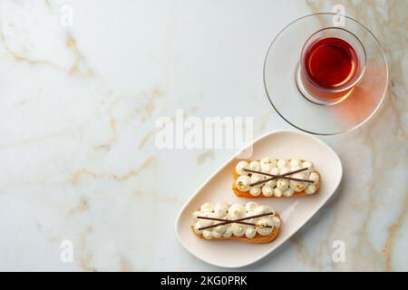 Two eclairs with white custard on whhite plate Stock Photo