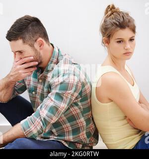 Theyve reached a stalemate. a young couple having relationship difficulties sitting back to back. Stock Photo
