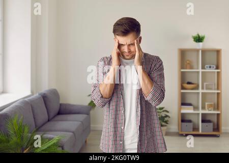 Tired, stressed, nervous, worried young man suffering from an intense headache at home Stock Photo