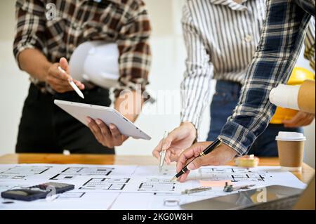 Group of professional Asian engineer are working together, discussing and planning their building process, using tablet and working on blueprint. crop Stock Photo