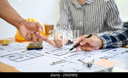 A team of professional Asian architect and engineer are working together, discussing and brainstorming on their building project, pointing pen on blue Stock Photo